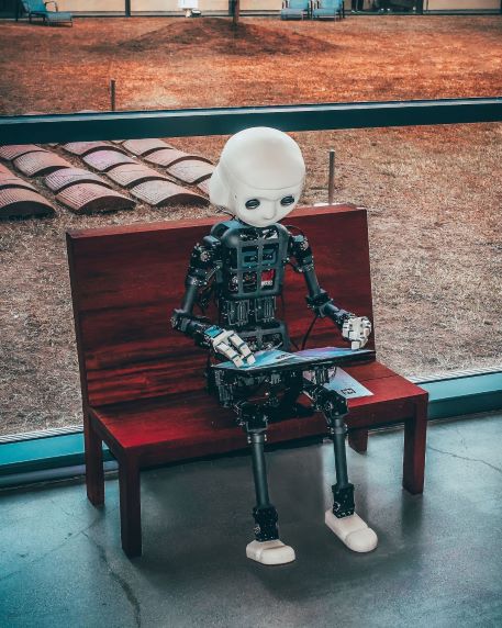 Humanoid robot reading on a bench